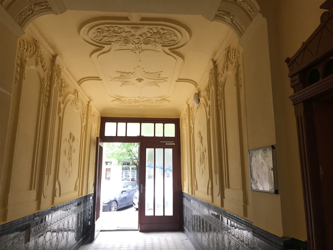 Restaurierter Altbau-Hauseingang mit aufwendiger Stuckdecke